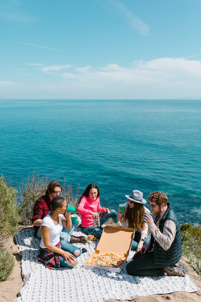 3 Women Sitting on Gray Rock Near Body of Water